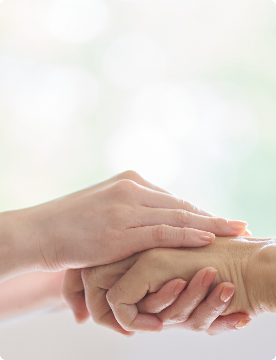 介護者が高齢者の手を優しく包み込んで支えている様子