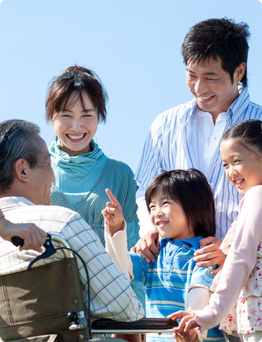 車椅子の高齢男性を囲んで家族が笑顔で過ごす様子