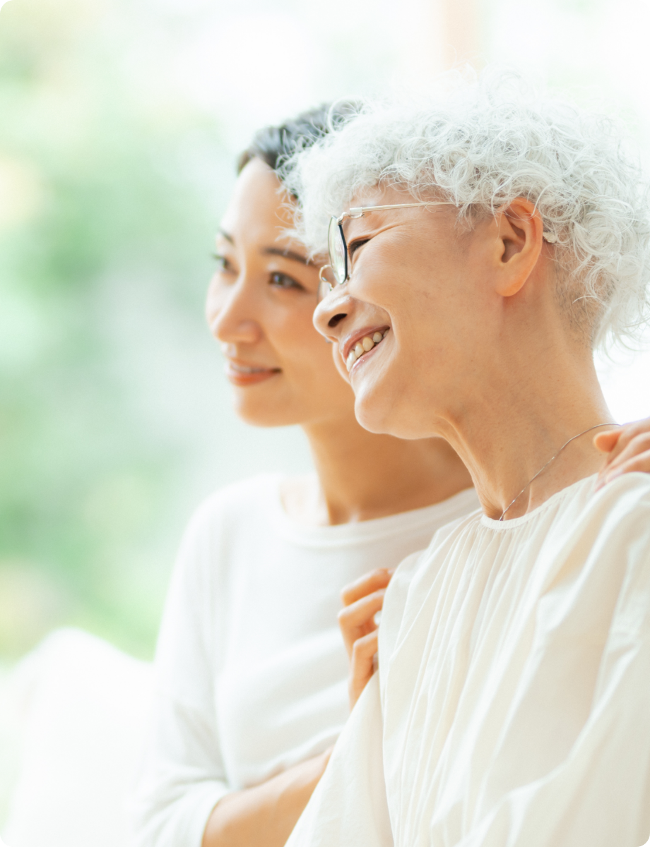 若い女性が高齢女性に寄り添い微笑む親子のような写真